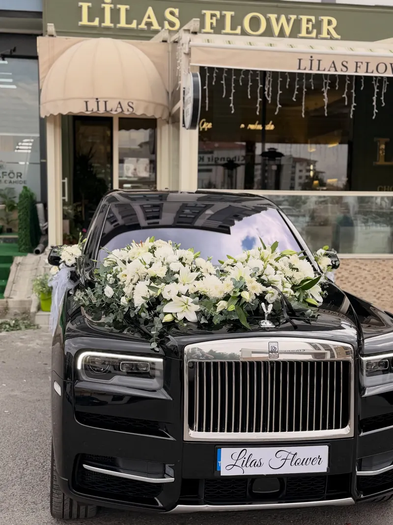 Altın harflerle LİLAS FLOWER yazan dükkân cephesi ve önünde beyaz çiçeklerle süslenmiş gelin arabası